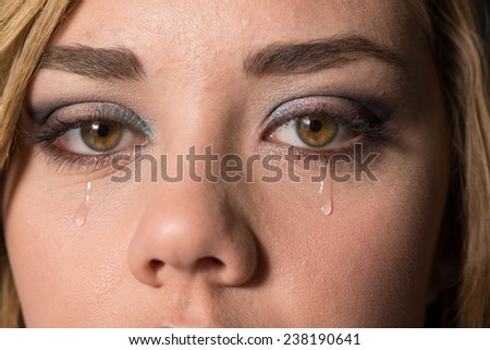 Teen girl crying, with a tear drop running down her cheek.
