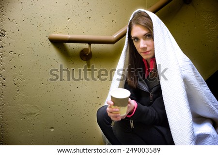 Young homeless woman sitting in a stairwell begging.