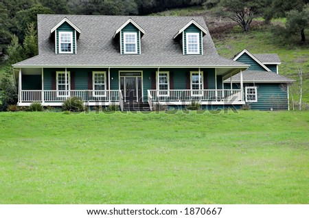 Large house in the country with dormer windows and wrap-around porch.