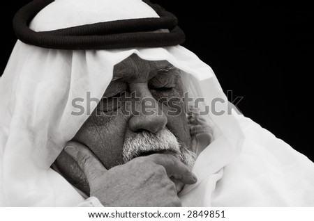 An older gentleman wearing Arabic headdress (a keffiyeh and agal), in contemplation.