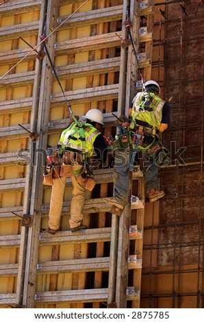 Two men working on the concrete form of a high wall.