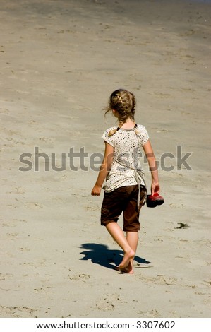 A young barefoot girl walking alone on a California beach