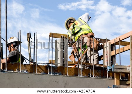 Workmen releasing a concrete form on a high wall.
