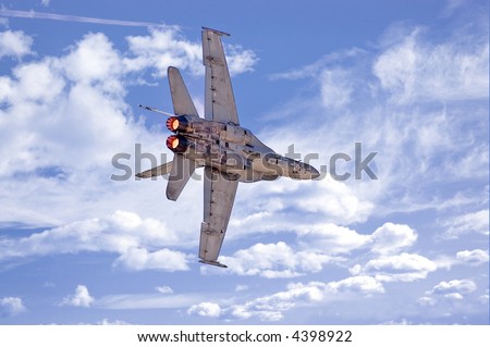 An F-18 Hornet making a banking turn against a cloudy sky.