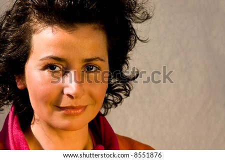 A curly-haired young woman against a plain background