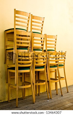Tall chairs from a restaurant, stacked outside early in the morning