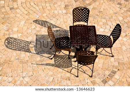 Patio furniture casting strong shadows across a patio tiled in a fan pattern