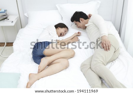 Asian couple laughing in bed