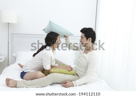 Asian couple disputing with pillows