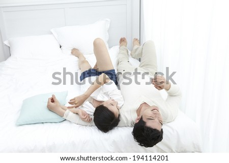 Asian couple laughing in bed