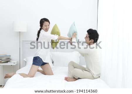 Asian couple having a pillow fight