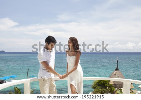 the image of Asian couple holding hands by the sea