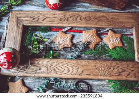 Happy holidays gingerbread cookies in a wooden frame with evergreens on a rustic background