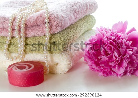 Three towels, soap and peony on a white background.