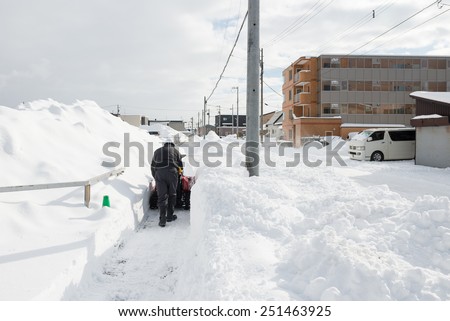 ENIWA, HOKKAIDO, JAPAN - JANUARY 13, 2015: Man Removing Snow with a Snow Blower.