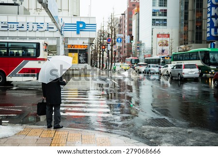 SAPPORO, JAPAN - JANUARY 6, 2015: Rear view of Businessman with umbrella standing on street.