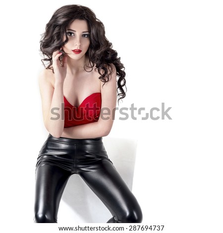 Fashion Sexy Woman Wearing Black Leather Pants and Red Top. Beautiful Young Model Girl with Long Curly Hair. Isolated on White.