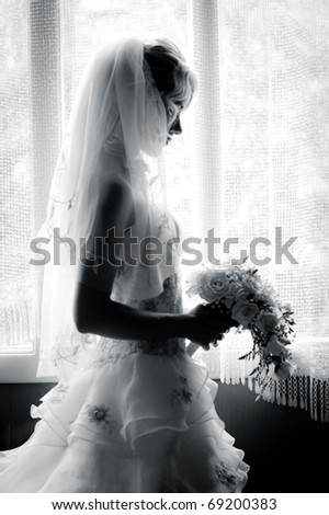 black and white silhouette of the bride weared in dress and veil with a bouquet