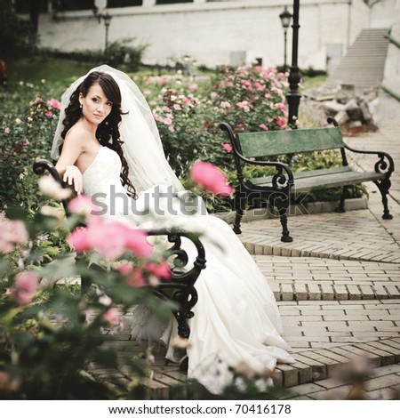  photo beautiful girl in a wedding dress sitting alone among the roses