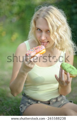 funny outdoor portrait of woman holding and eating dough-nuts