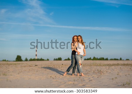 Two beautiful women staying together on sand outdoor