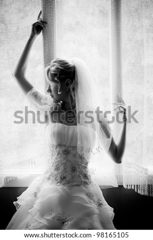 black and white silhouette of the bride weared in dress and veil  near the window