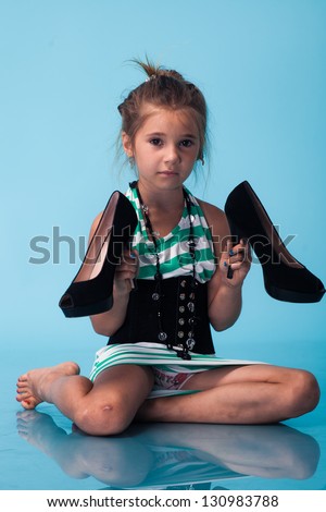 little girl wearing big mothers shoes on blue background