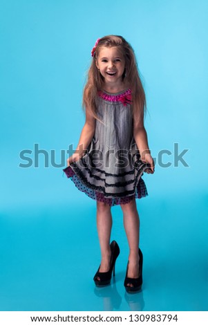 little girl wearing big mothers shoes on blue background