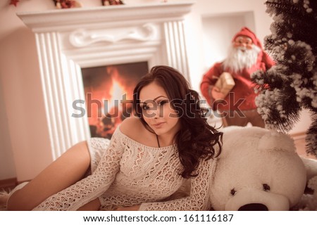 Beautiful young girl sitting beside the fireplace and Christmas tree