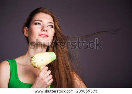 Portrait of young beautiful woman with hair dryer isolated on black