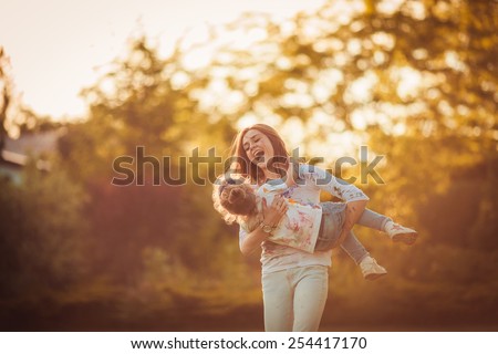 Mother and little daughter playing together in a park