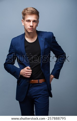 Portrait of handsome guy in suit posing in studio on gray background