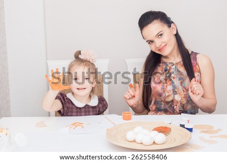 Mother and daughter painting Easter holiday eggs