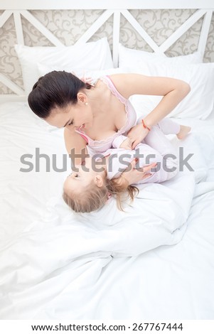 Mother and daughter lying in soft bed