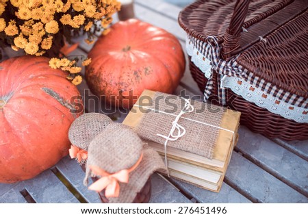 Flowers, pumpkins, jam, books and basket on garden table