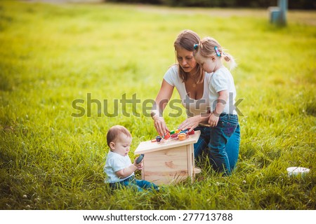 Happy family painting wooden parts of birdhouse in garden