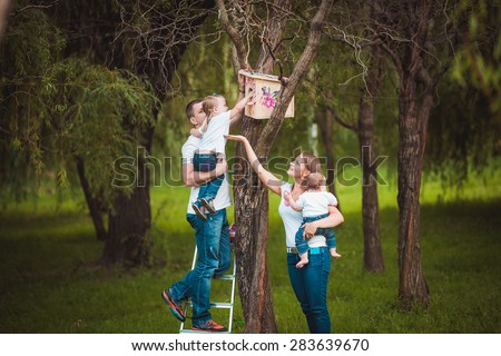 Happy family with Wooden birdhouse feeding the bird on tree in summer green forest