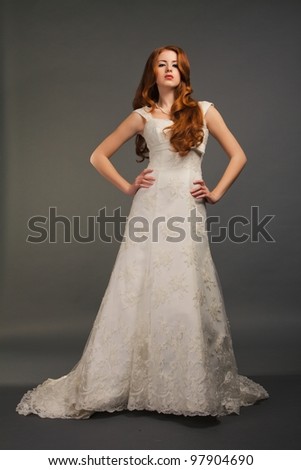 beautiful bride with curly red hair in luxury wedding dress with tail