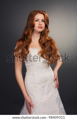 beautiful bride with curly red hair in luxury wedding dress with tail