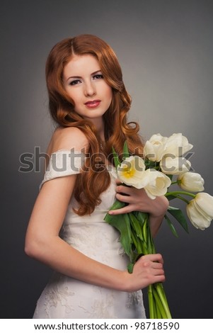 beautiful bride with curly red hair in wedding dress with flowers