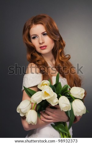 beautiful bride with curly red hair in wedding dress with flowers