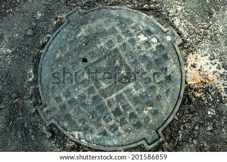 Manhole with metal cover in asphalt surface
