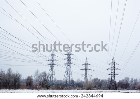 System of electricity pylons and power lines out-of-town in the winter day.