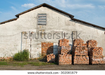 Stacks of bricks on wooden pallets near the old gray house
