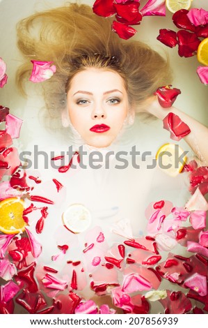 luxury spa queen: elegant blue eyes pinup girl with silk skin having fun laying in water bath & looking at camera relaxing on colorful copy space background, close up portrait