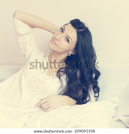 closeup on glamor brunette young pretty woman having fun happy relaxing lying in bed happy smiling & looking at camera posing on light copy space background, portrait