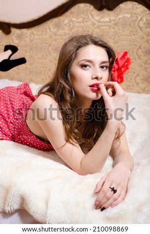 closeup portrait of looking at camera thoughtfully beautiful pinup girl with red lipstick having fun relaxing in bed on light copy space background