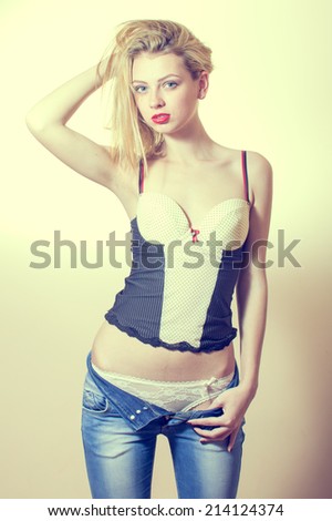 beautiful gorgeous young blonde lady having fun posing showing her excellent fitness slim body undressing jeans on white or light copy space background