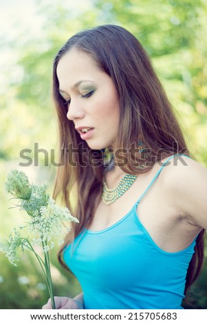 closeup portrait of beautiful brunette young woman having fun relaxing holding field flower on summer green outdoors copy space background