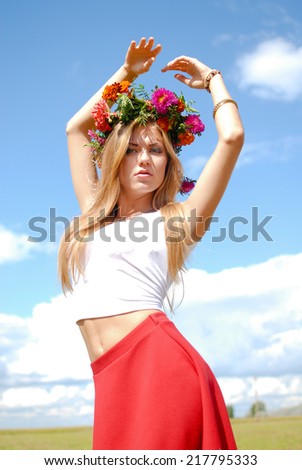 summer dancing series: portrait of beautiful blonde young lady wearing flower crown having fun on summer outdoors copy space background & looking at camera